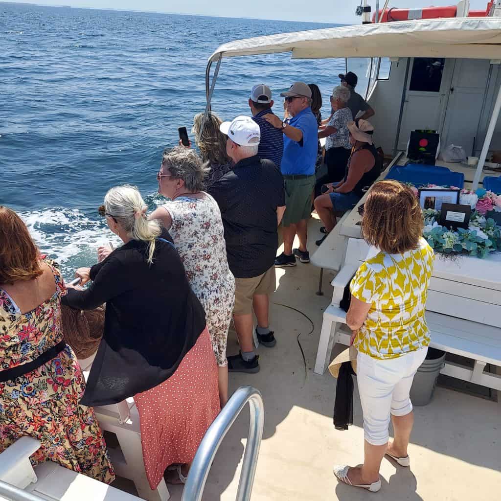 family and friends gathered on a eternal peace sea burial boat for a memorial service.
